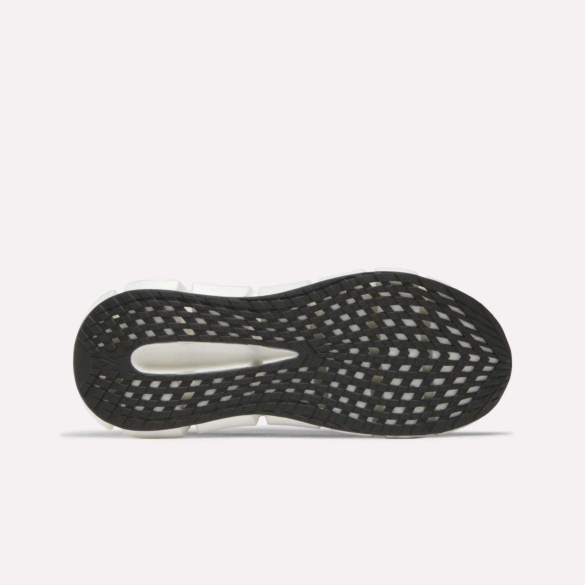 The image shows the sole of Reebok Men's FloatZig 2 Running Shoes featuring a black and white geometric tread and an elongated oval cutout in the midfoot, designed to enhance Superfloat+ cushioning.