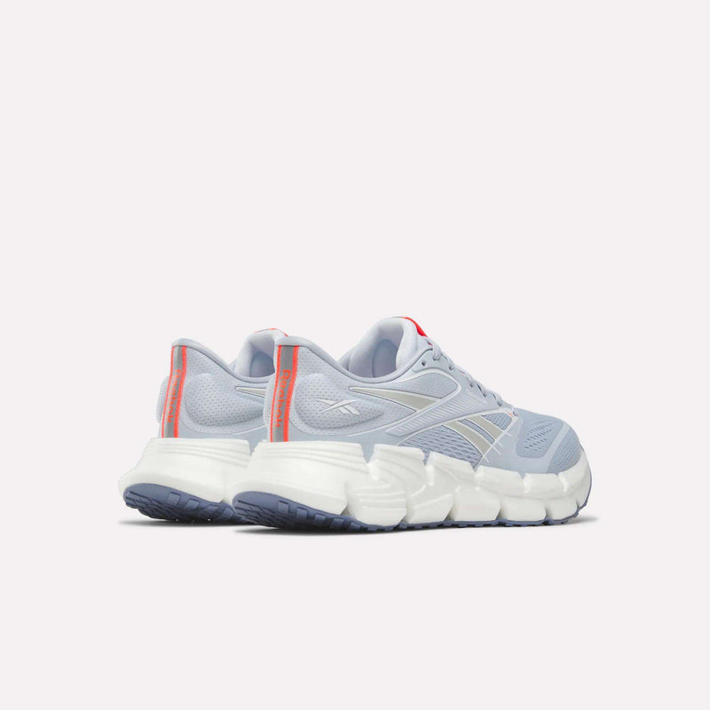 A pair of Reebok Women's FloatZig 2 Running Shoes in light blue with Superfloat+ cushioning, white soles, gray accents, and red-orange heel tabs, displayed rear view on a plain white background.