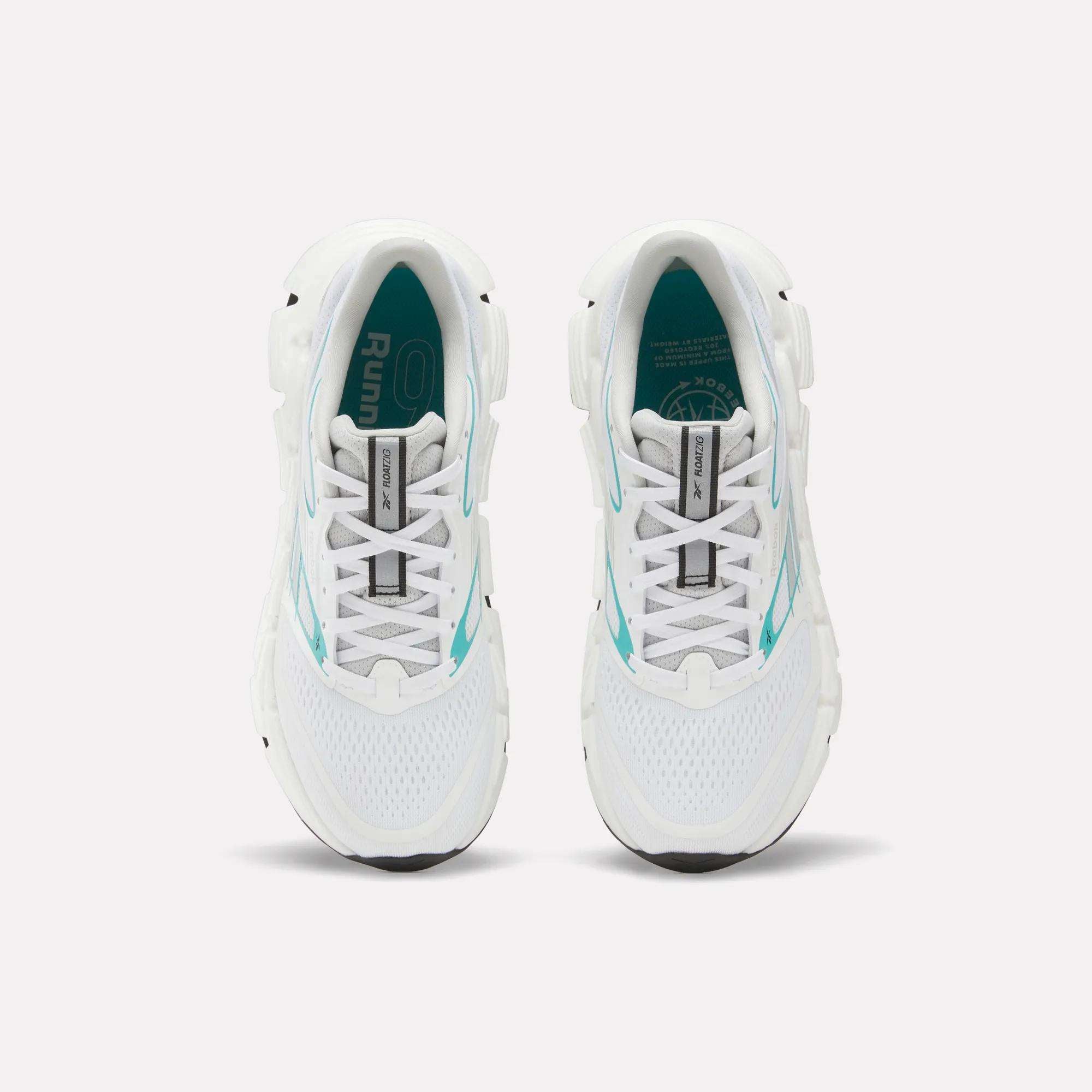 Top view of a pair of white Reebok Women's FloatZig 2 Running Shoes with turquoise accents and black soles on a plain white background. The insoles feature branding and design details, highlighting their springy cushioning.