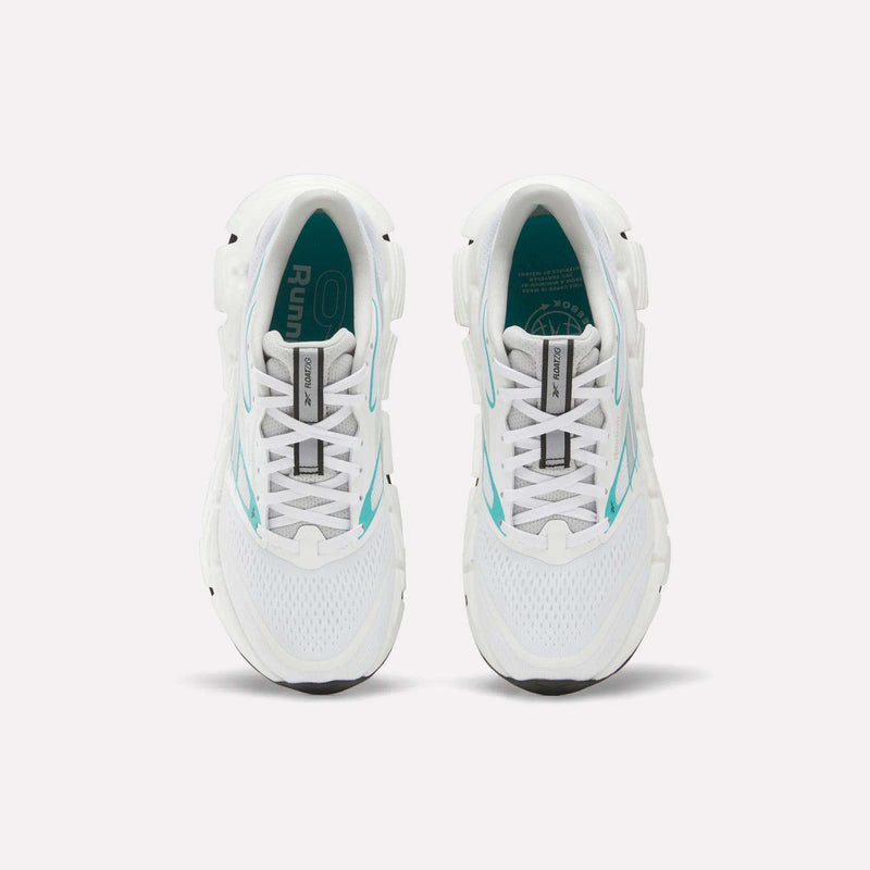 Top view of a pair of white Reebok Women's FloatZig 2 Running Shoes with turquoise accents and black soles on a plain white background. The insoles feature branding and design details, highlighting their springy cushioning.