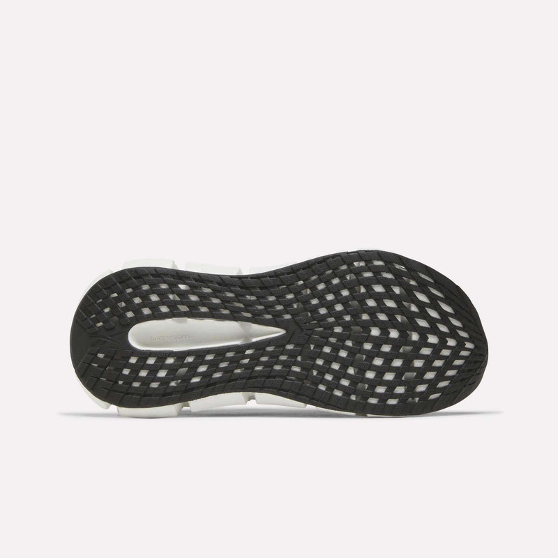 The image displays the black and white sole of Reebok Women's FloatZig 2 Running Shoes, viewed from beneath. The tread has a crisscross grid for traction, and Superfloat+ cushioning provides a springy feel.