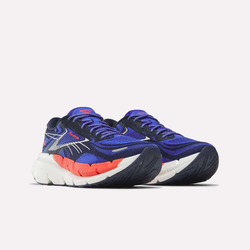 The Reebok Men's FloatZig Double Running Shoes feature blue cushioning, purple accents, red midsole details, and thick white and black StableStack soles, displayed on a white background.