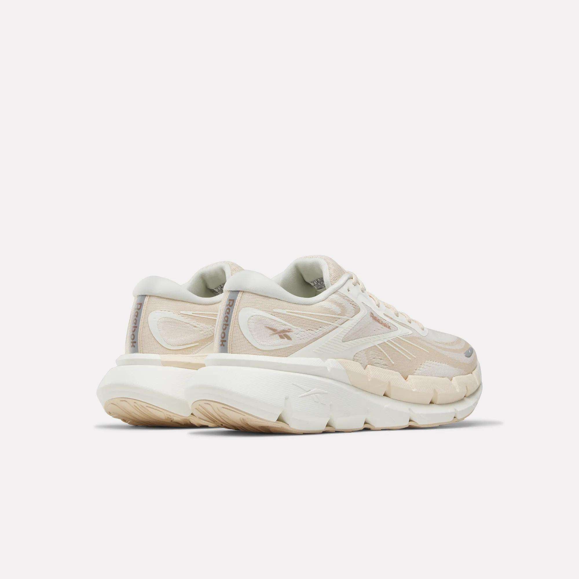 A pair of Women's FloatZig Double Running Shoes by Reebok in chunky off-white with beige accents and thick, textured soles—perfect for max-cushioned miles—viewed from the back left side against a plain light background.