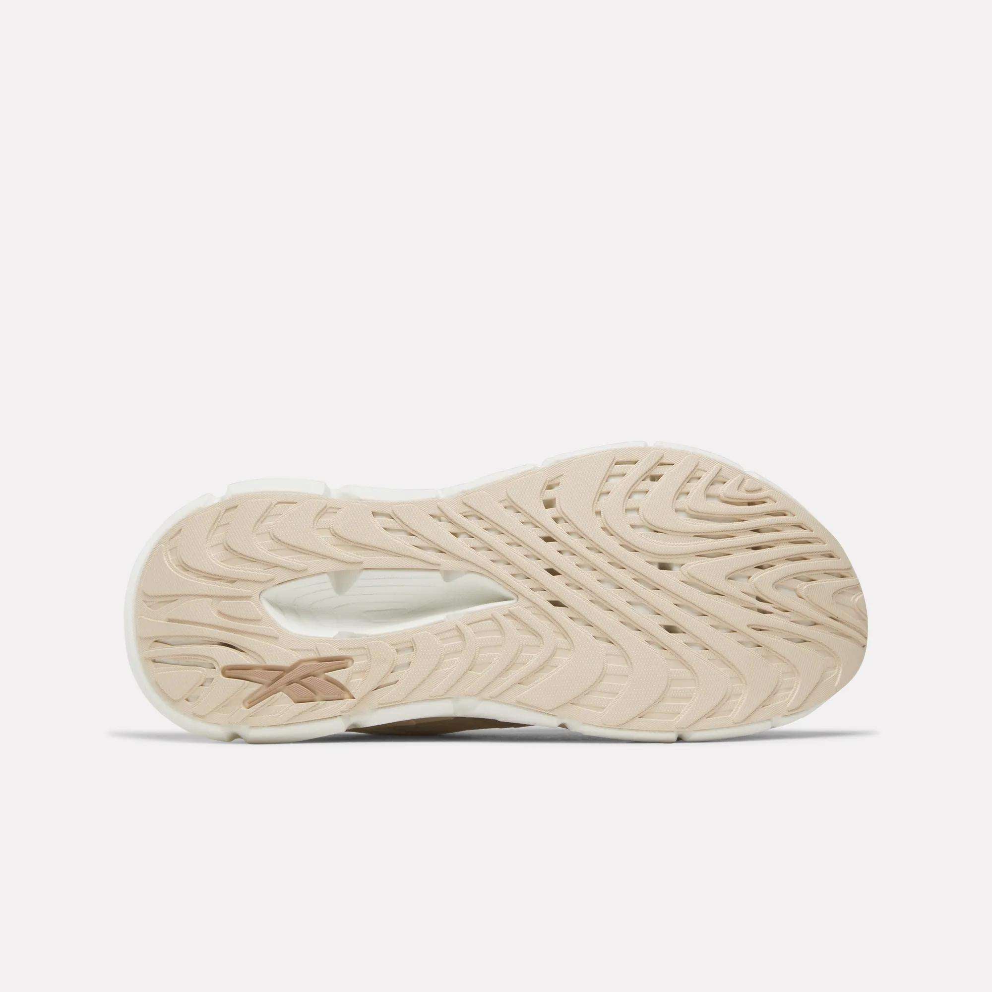 Beige and white textured sole of the Reebok Women's FloatZig Double Running Shoes, featuring wavy patterns and a small star-like logo, shown from the bottom against a plain white background.