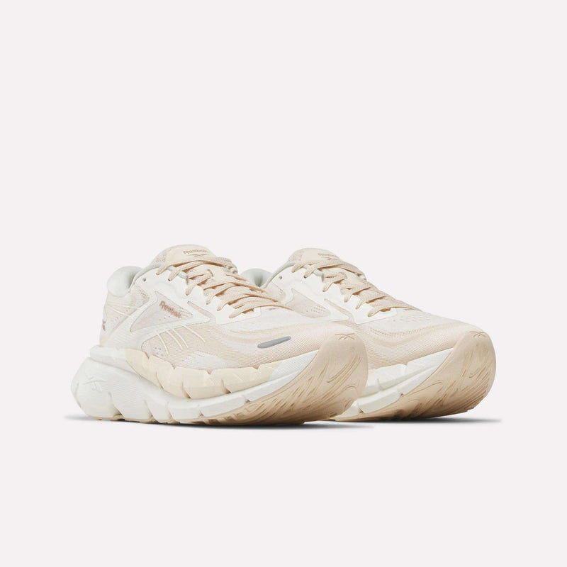 A pair of Reebok Women's FloatZig Double Running Shoes in beige and off-white with thick, textured soles and subtle branding, shown on a white background—crafted for maximum cushioning and comfort during your runs.