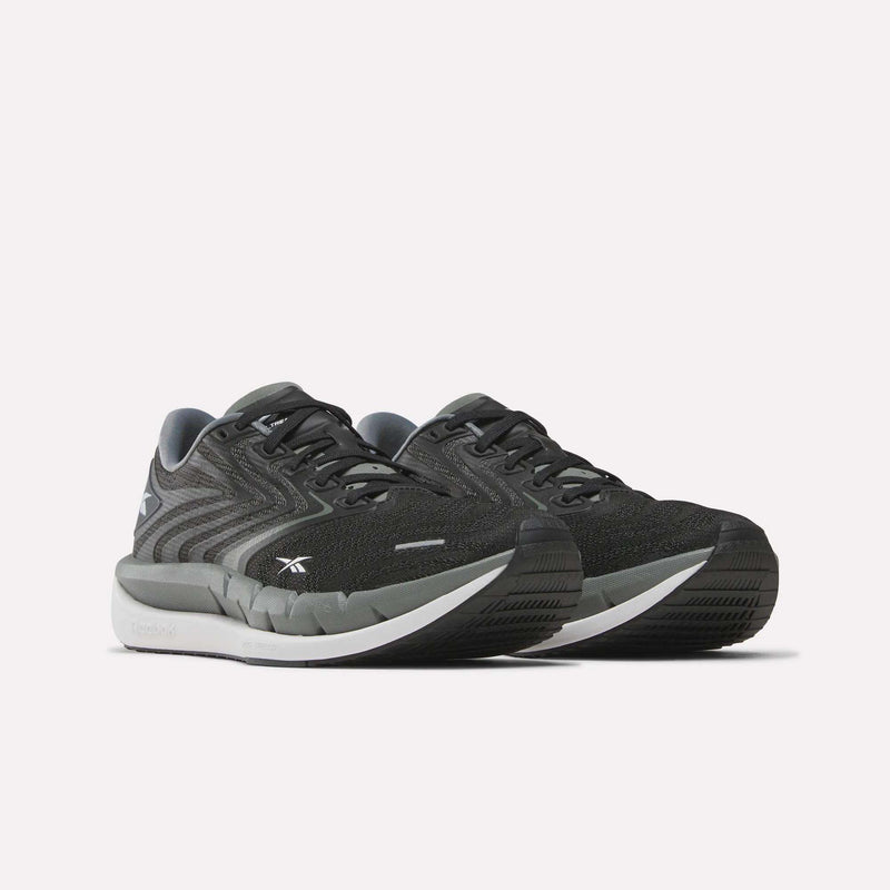 A pair of Reebok Women’s FloatZig Tread Running Shoes in black and gray with breathable mesh uppers and white soles, displayed on a plain white background.
