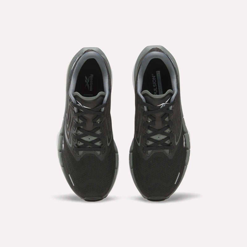 A pair of Women’s FloatZig Tread Running Shoes by Reebok, shown from above to display the black breathable mesh uppers, laces, and Reebok logos on the insoles. The sneakers are set against a plain white background.