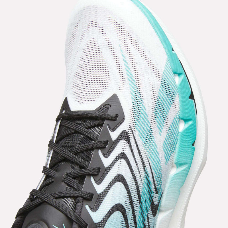 A close-up of the Reebok SpeedShifter Running Shoe showcases its white mesh upper adorned with black laces and striking black and teal wave designs. The light teal midsole complements the modern, dynamic pattern, while HyperFloat foam cushioning delivers superior comfort with every stride.