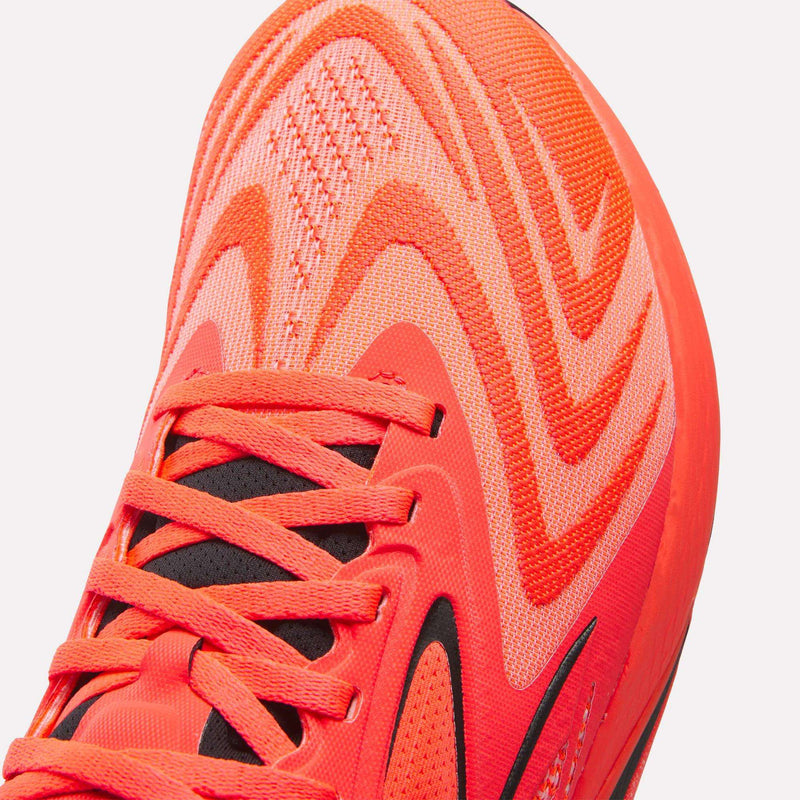 Close-up of the front of the Reebok Nano X5 Edge Training Shoes in bright orange, featuring wavy patterns, black detailing, and matching orange laces—engineered for peak performance.