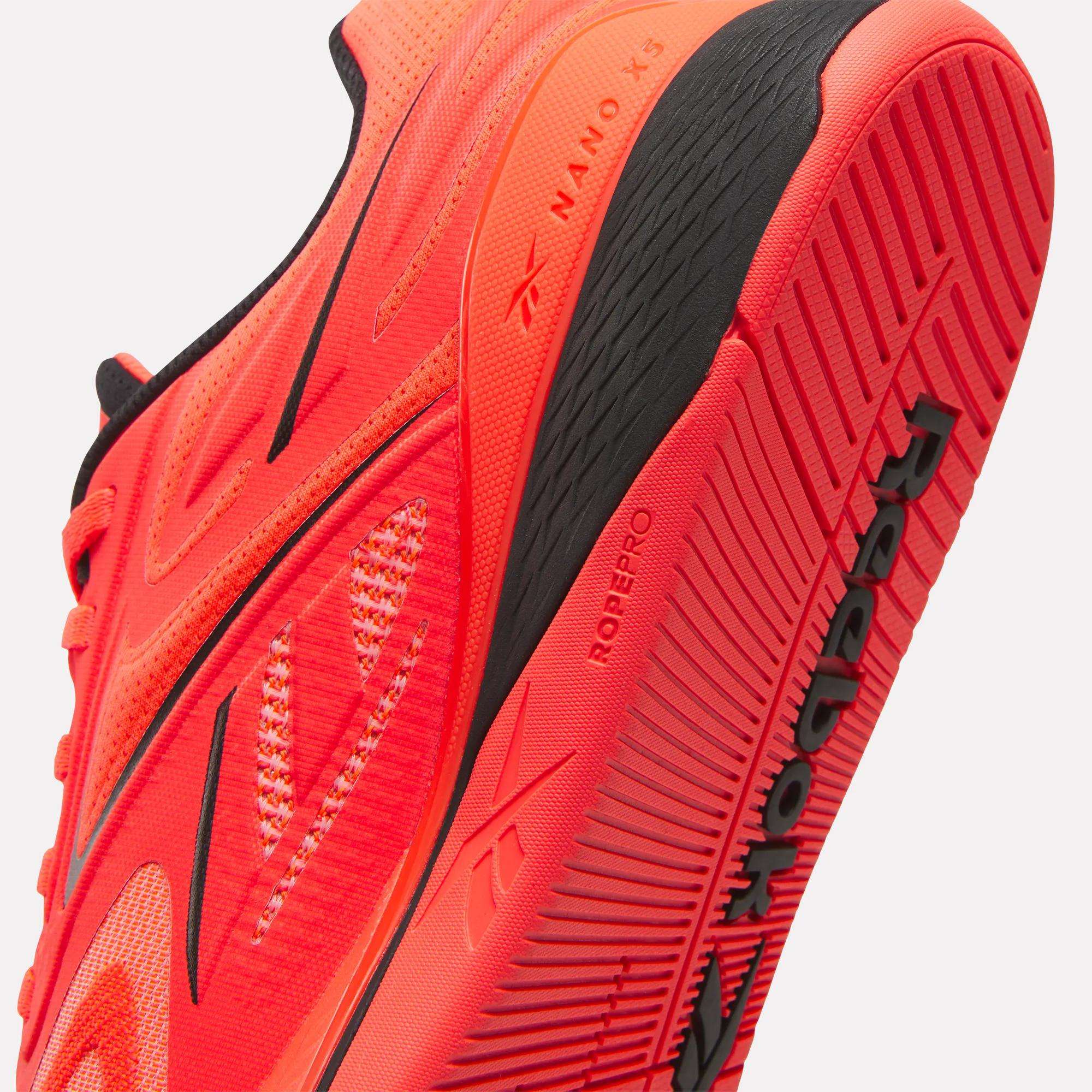 Close-up of a vivid red Reebok Nano X5 Edge Training Shoe with black accents, focusing on the sole and side details to showcase the advanced performance features of this Reebok model.