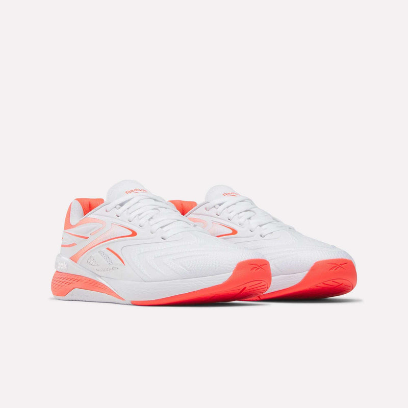 A pair of Reebok Women's Nano X5 Edge Training Shoes in white with bright coral accents and soles are displayed on a plain light background, facing slightly right.