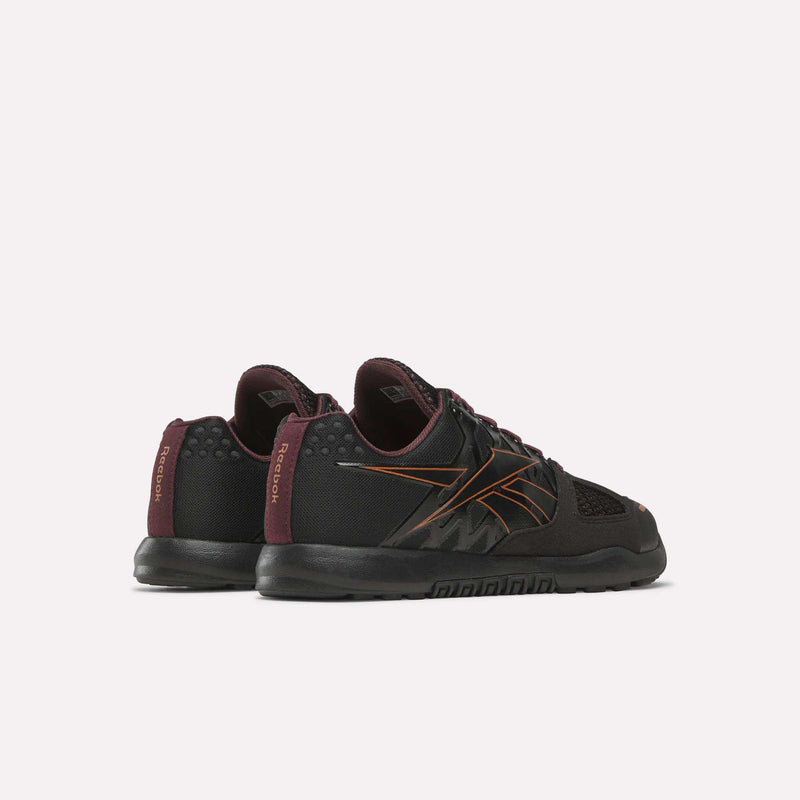 A pair of Women’s Nano 2.0 Training Shoes by Reebok in black with maroon and orange accents, shown from the rear angled view to highlight the heel and outer details—ideal women’s training shoes for functional fitness routines.