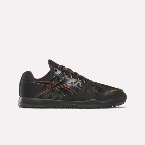 A side view of the Women’s Nano 2.0 Training Shoes by Reebok is shown against a plain white background, highlighting their black and copper colorway, mesh panel detailing, and textured sole—features that showcase the sleek design and functional fitness performance characteristic of Reebok training footwear.