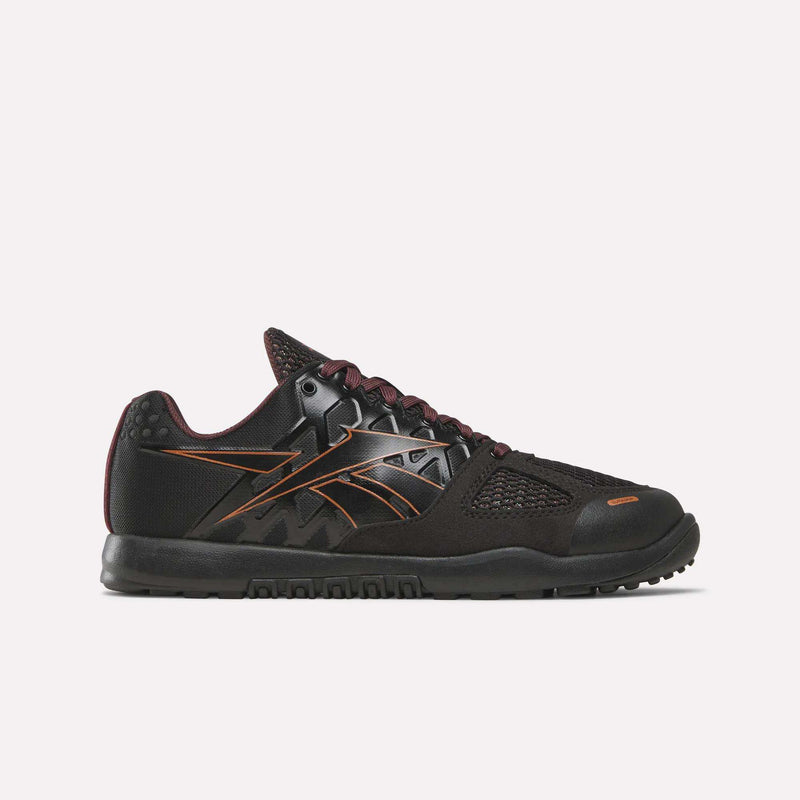 A side view of the Women’s Nano 2.0 Training Shoes by Reebok is shown against a plain white background, highlighting their black and copper colorway, mesh panel detailing, and textured sole—features that showcase the sleek design and functional fitness performance characteristic of Reebok training footwear.