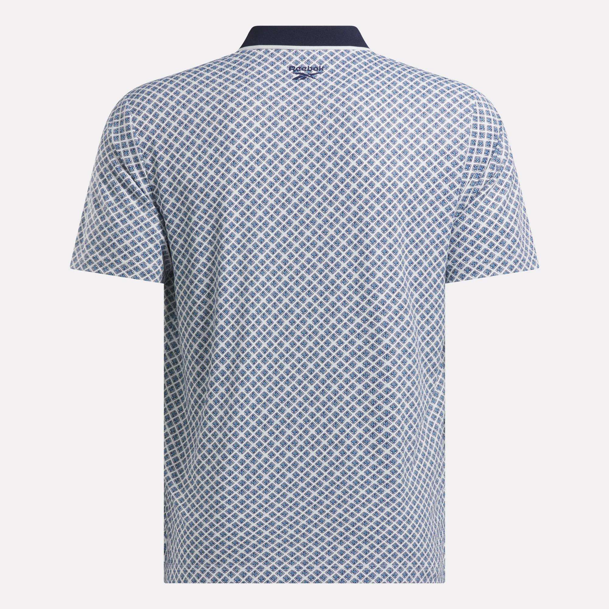 Back view of the Men’s Sublimation Print Shirt by Reebok, featuring a sweat-wicking fabric, blue and white diamond pattern, dark collar, and the Reebok logo at the upper back below the collar.