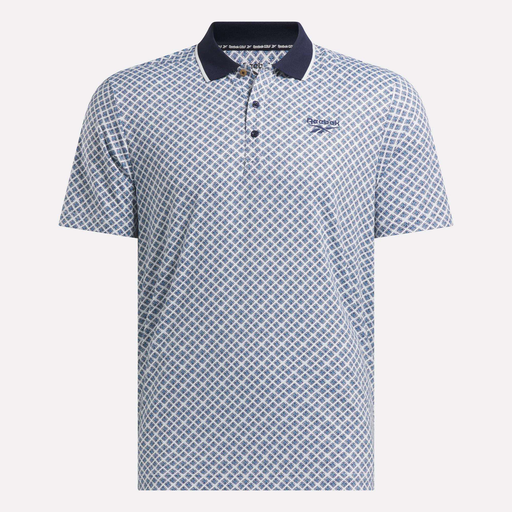 The Reebok Men's Sublimation Print Shirt features short sleeves, a blue and white geometric pattern, a dark blue collar, sweat-wicking fabric, and a small Reebok logo on the left chest.