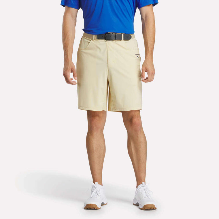 A man wearing a blue shirt and Reebok Men's Favorite 5-Pocket Golf Shorts 9".
