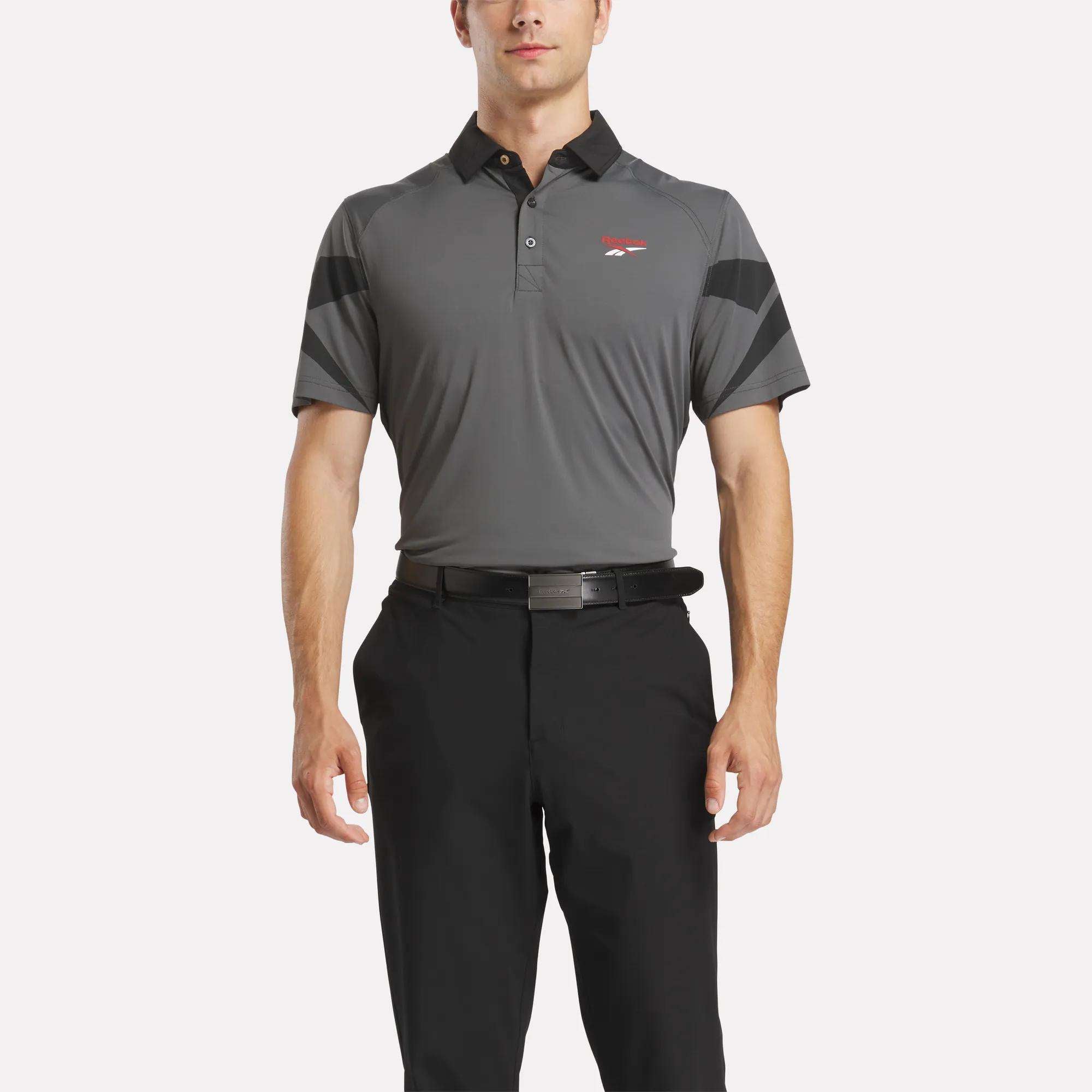 A man wearing a grey Reebok Men's Signature Vector Colorblocked Polo Shirt.