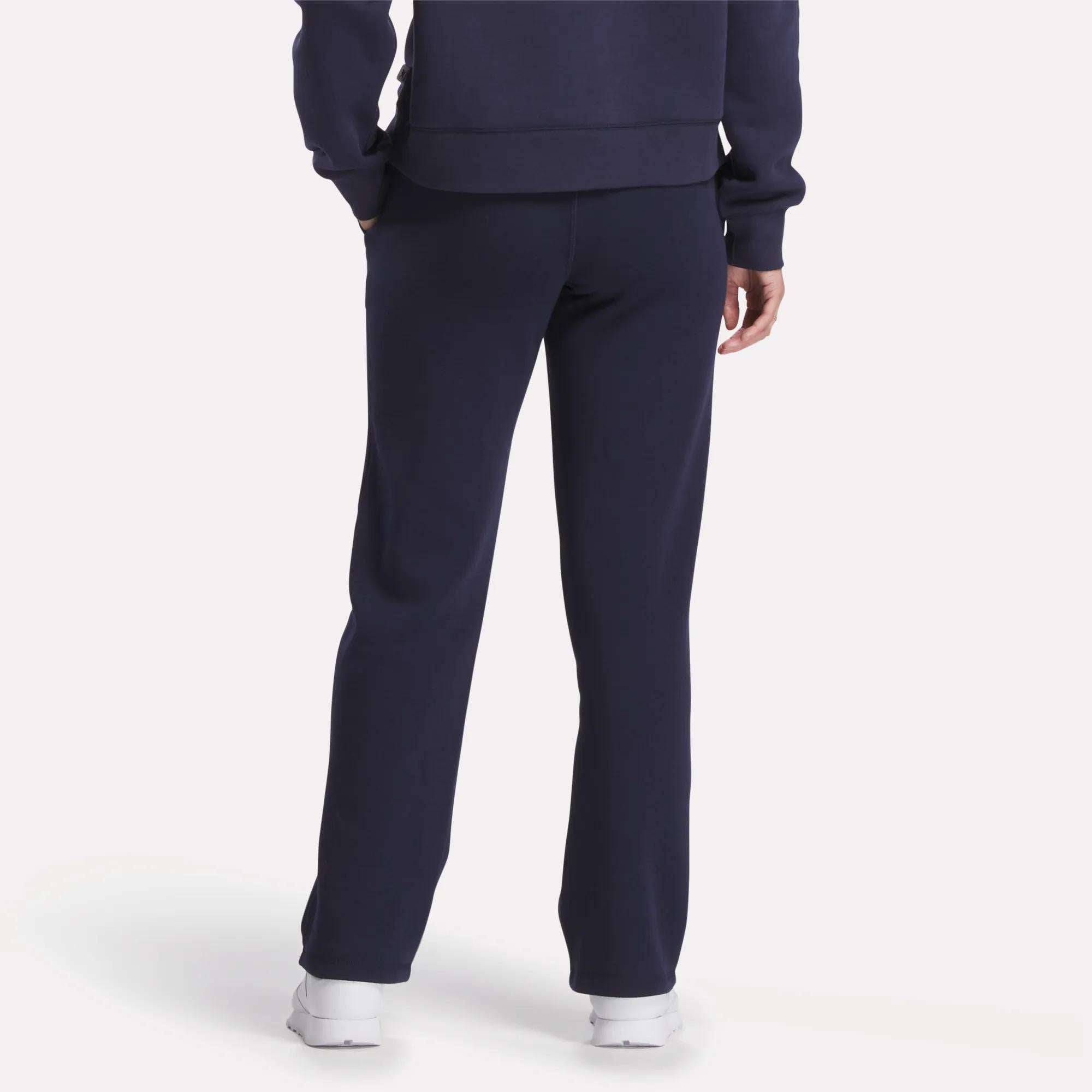 Person wearing navy blue cotton blend sweatshirt and matching Women's Cozy Classic Sweatpants by Reebok, standing with back to the camera and also wearing white sneakers.