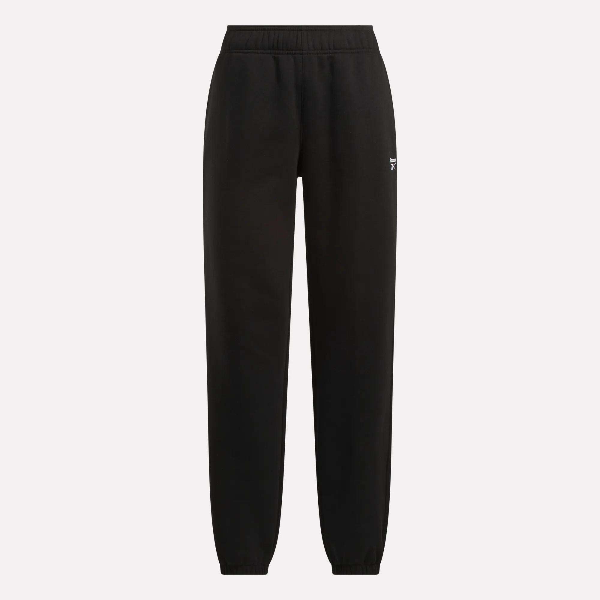 Reebok Women's Medium Vector Sweatpants in black with an elastic waistband and cuffed ankles, shown on a plain light background. Crafted from soft cotton-blend fabric with a small white Reebok logo on the upper left thigh.