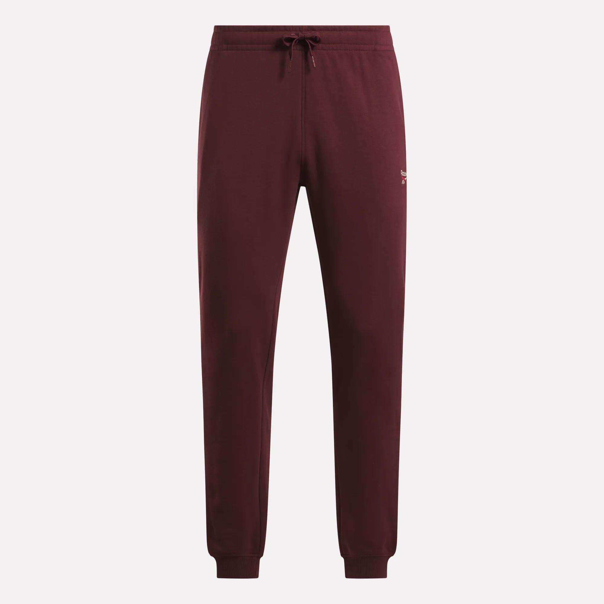 Reebok Men's French Terry Logo Joggers in maroon, featuring a drawstring waist, ribbed cuffs, and a small white logo on the left hip, shown against a plain light background.