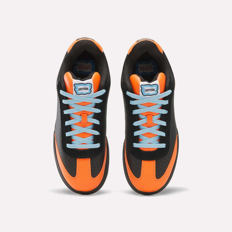 Pair of black and orange Reebok x Icecream Board Flip Shoes featuring a low-top suede design, light blue laces, and Icecream brand logos on the tongues and insoles.