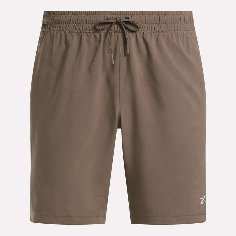 Reebok Men's Woven Shorts in brown feature an elastic waistband, drawstring, and a small white logo on the lower left leg. These sweat-wicking shorts have a simple design and are shown against a plain background.