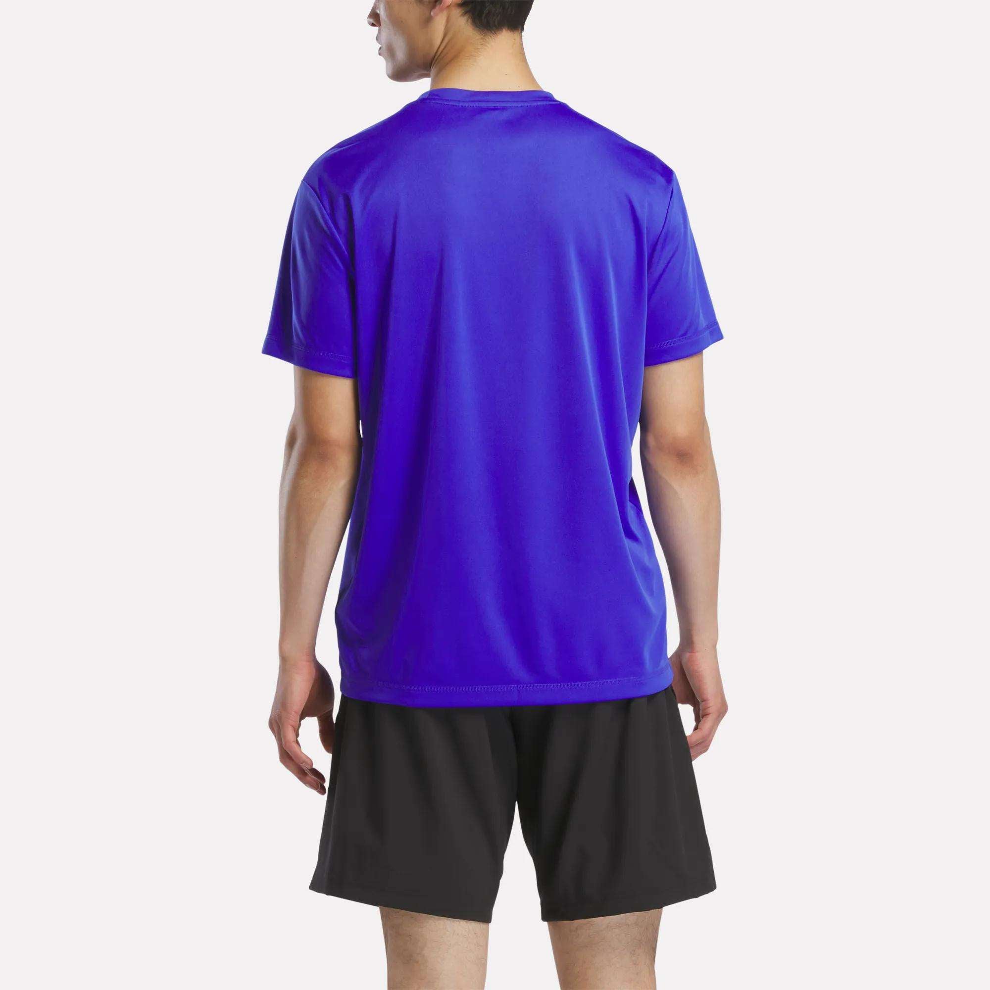 A person stands with their back to the camera in a bright blue Reebok Men's Short Sleeve Tech Training T-Shirt and black shorts, set against a plain white background.