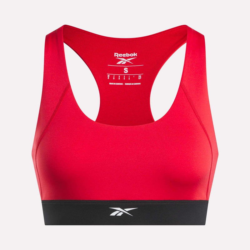 A red Reebok Women's Racer Sports Bra featuring a supportive racerback design, contrasting black band at the bottom, and mid-impact support. The Reebok logo appears on the inner back and front band, making it an ideal choice for reliable workout performance.