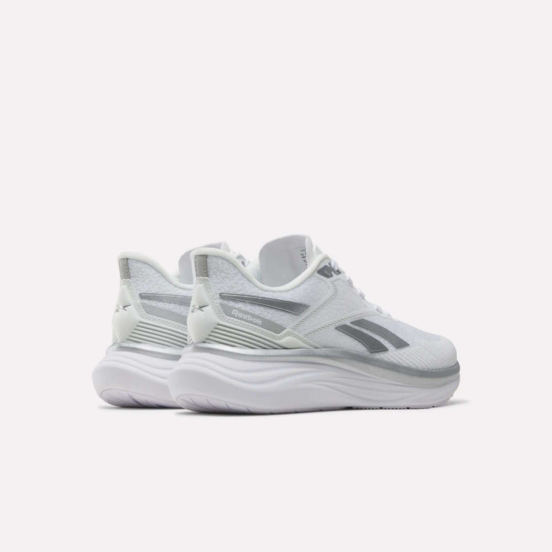A pair of Reebok Women’s Viva Speed Shoes in white with gray accents, designed with extra cushioning for enhanced comfort, displayed from a rear-side angle on a plain light background.