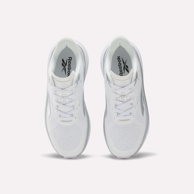 Top view of a pair of Reebok Women’s Viva Speed Shoes in white with gray accents, featuring extra cushioning for enhanced comfort, placed side by side on a plain white background. The Reebok logo is visible on the insoles.