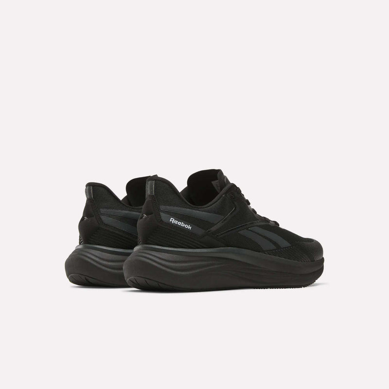 The Reebok Men's Viva Speed Shoes, shown from a rear side angle on a white background, feature black mesh uppers and thick wavy soles, delivering a perfect mix of breathability and cushioned comfort.