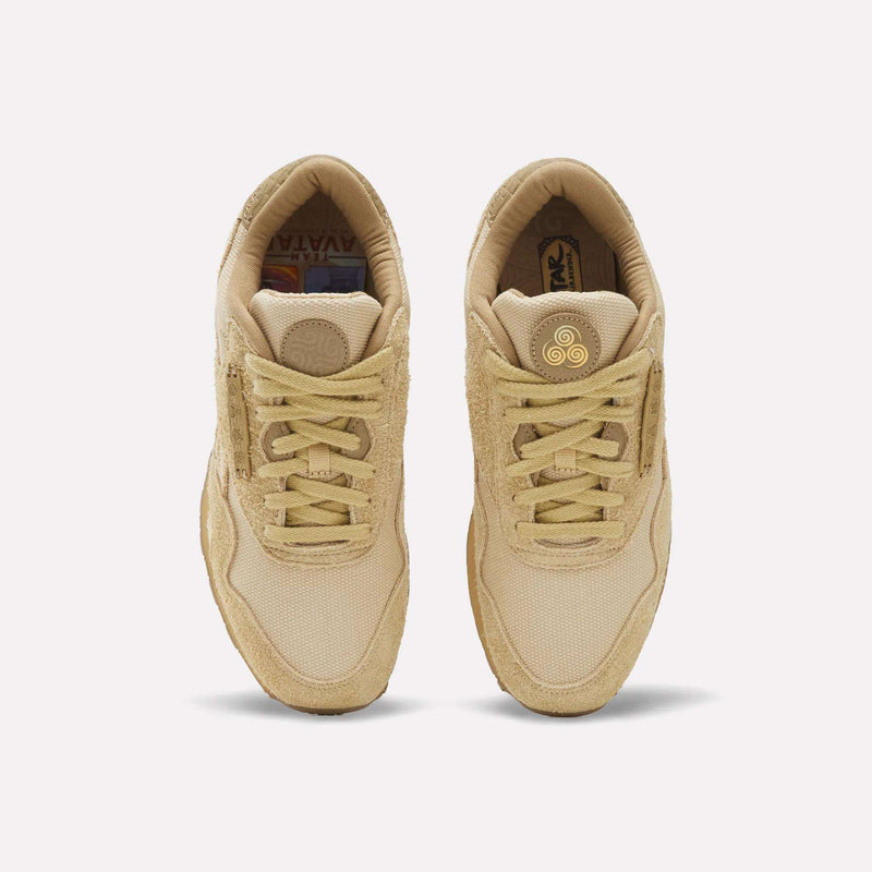 Top-down view of tan Reebok x Avatar Classic Nylon Shoes with a circular gold emblem on each tongue and Team Avatar graphics on the insoles.