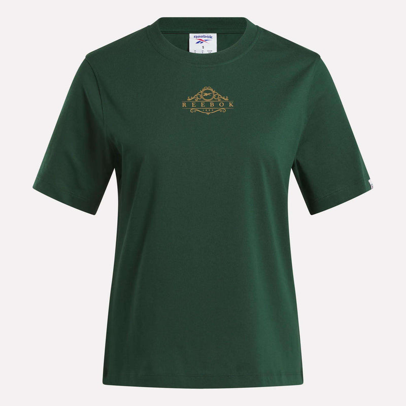 The Women's Fitted Graphic T-Shirt by Reebok features a plain dark green design with short sleeves, a crew neckline, and a small gold Reebok logo with a decorative detail on the chest. Made from soft cotton, this durable graphic tee delivers comfort and classic everyday style.