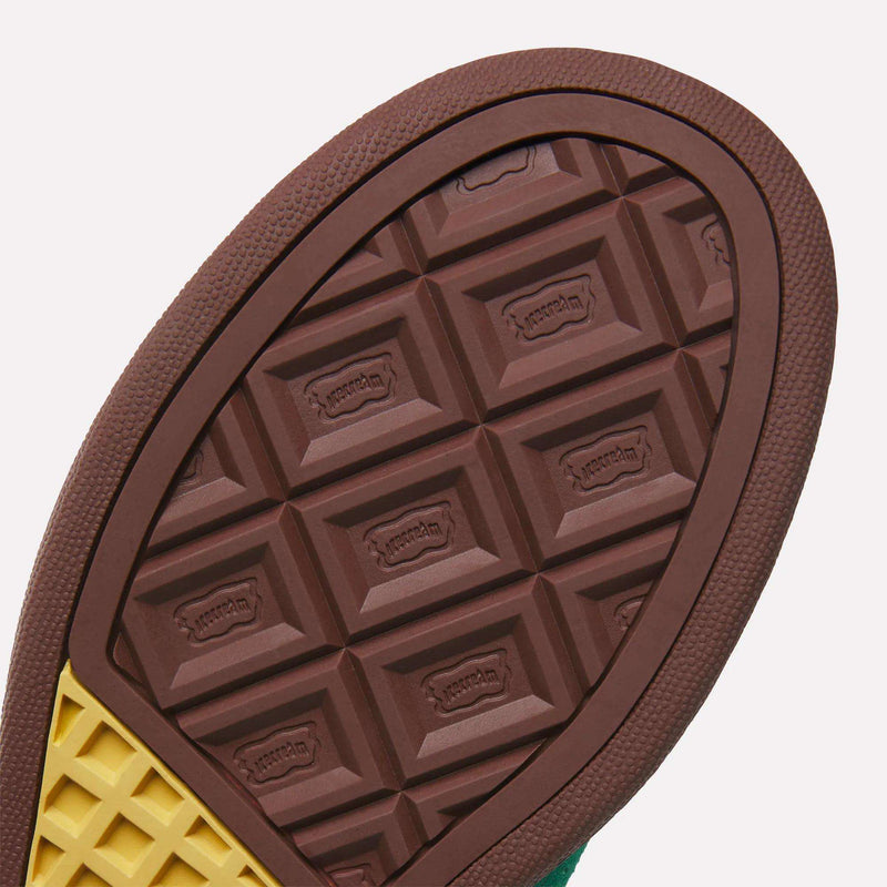 Close-up of the Reebok x BBC Board Flip Skate Shoes sole, featuring a brown and yellow waffle-patterned tread with embossed Vibram logos in rectangles, reminiscent of early-2000s skate shoe style.