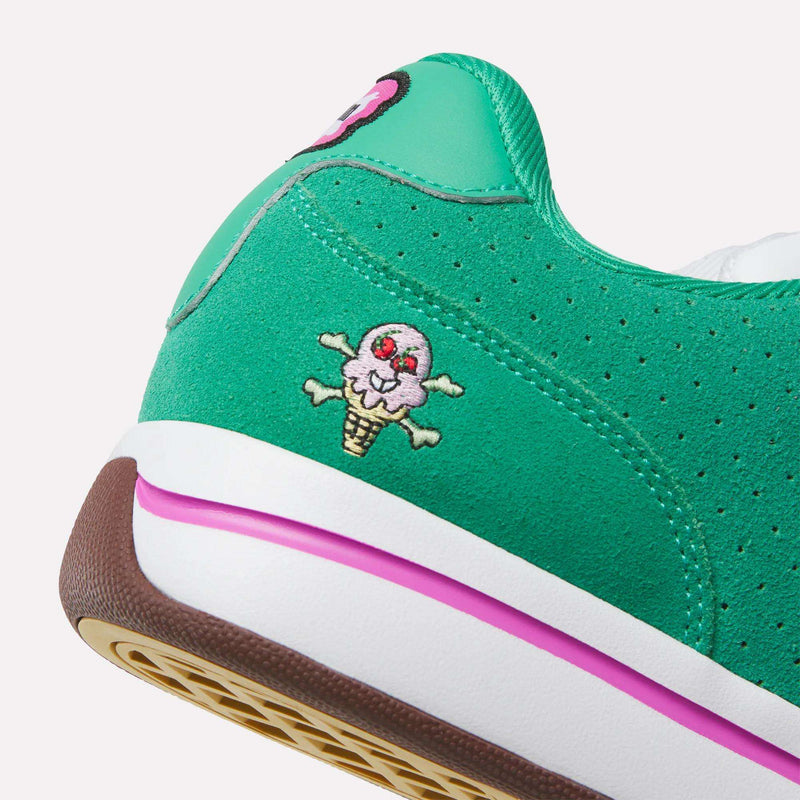 Close-up of the Reebok x BBC Board Flip Skate Shoes in green, featuring an embroidered skull ice cream cone on the heel, a white midsole with pink stripe, and a brown rubber outsole—channeling early-2000s style.
