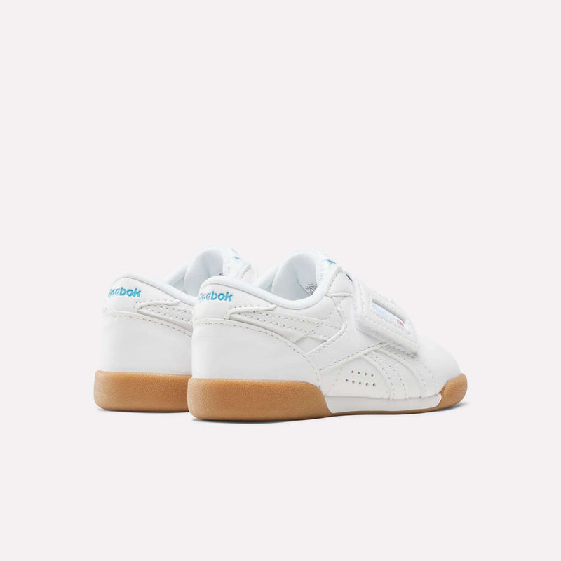 White Reebok Freestyle Lo Shoes - Baby & Toddler sneakers with gum rubber soles and a hook-and-loop strap closure, featuring an ’80s aerobics style.
