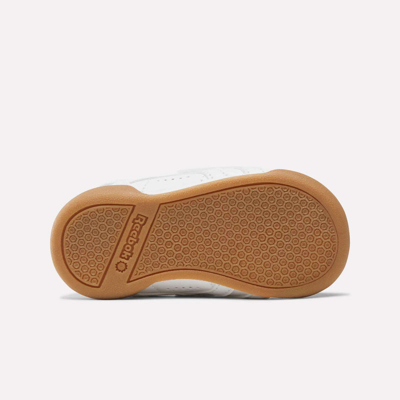 Bottom view of a Freestyle Lo Shoes - Baby & Toddler Reebok sneaker showing a brown rubber sole with a hexagonal tread pattern and the brand name embossed in the center.