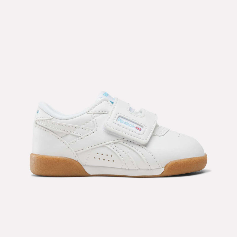 Reebok Freestyle Lo Shoes - Baby & Toddler in white with a blue accent, hook-and-loop strap, and gum rubber sole, inspired by ’80s aerobics style.