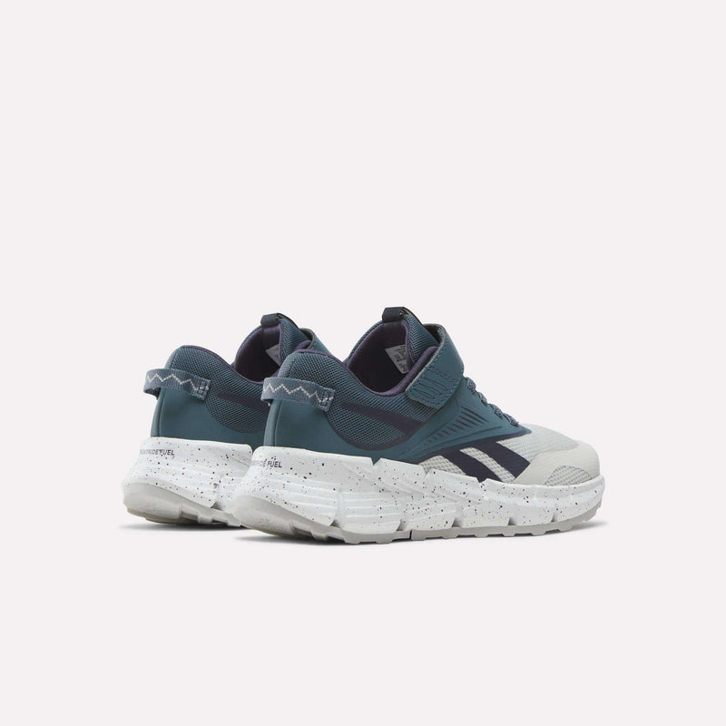 A pair of Reebok Zig Dynamica 6 Running Shoes for little kids, featuring dark blue and gray uppers, white speckled soles, Velcro straps, and a zigzag detail on the heel with innovative Reebok Zig technology, shown against a plain light background.