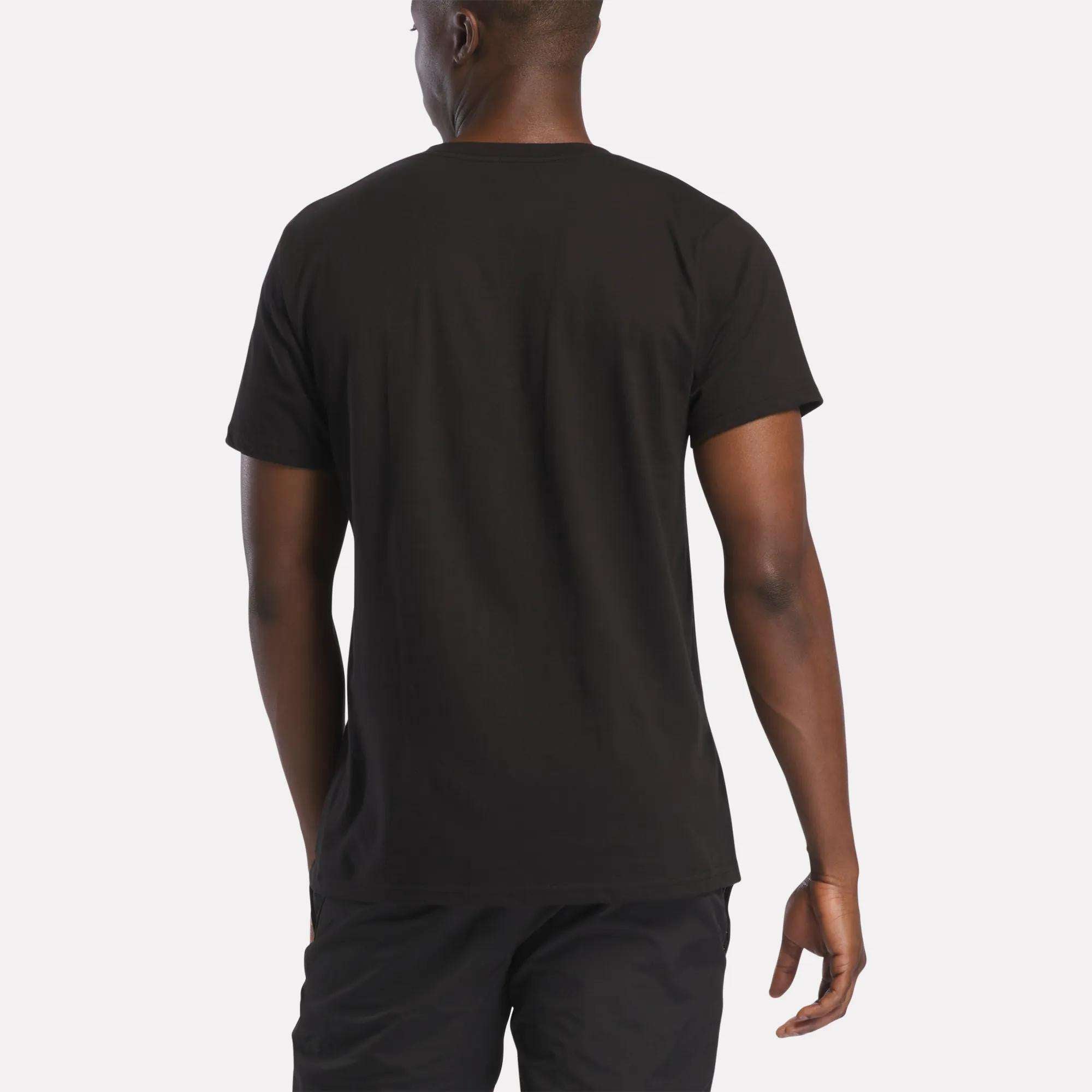 A person is standing with their back to the camera, wearing a Reebok Men's Vector Graphic Rainbow T-Shirt and black shorts against a light background.