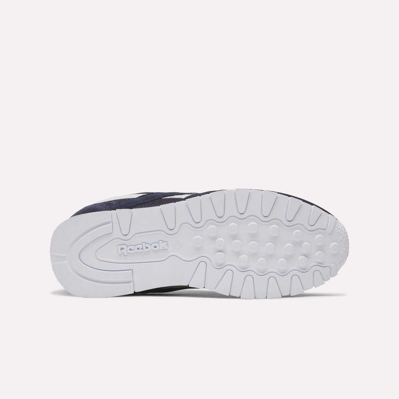 A close-up view of the underside of the Reebok Classic Nylon Shoes - Big Kids reveals a white rubber sole with textured treads and the embossed Reebok logo near the heel—a stylish detail typical of boys’ footwear from Reebok.