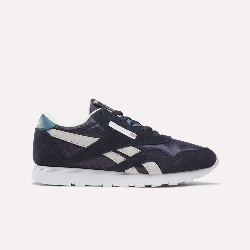 A pair of Reebok Classic Nylon Shoes for Big Kids in Dark Indigo, New Grey 1, and Midnight Tide is shown in profile against a plain light background. Featuring a white sole, dark indigo suede overlays, and crisp side stripes, these sneakers combine comfort with timeless style—making them an excellent choice for boys’ footwear.