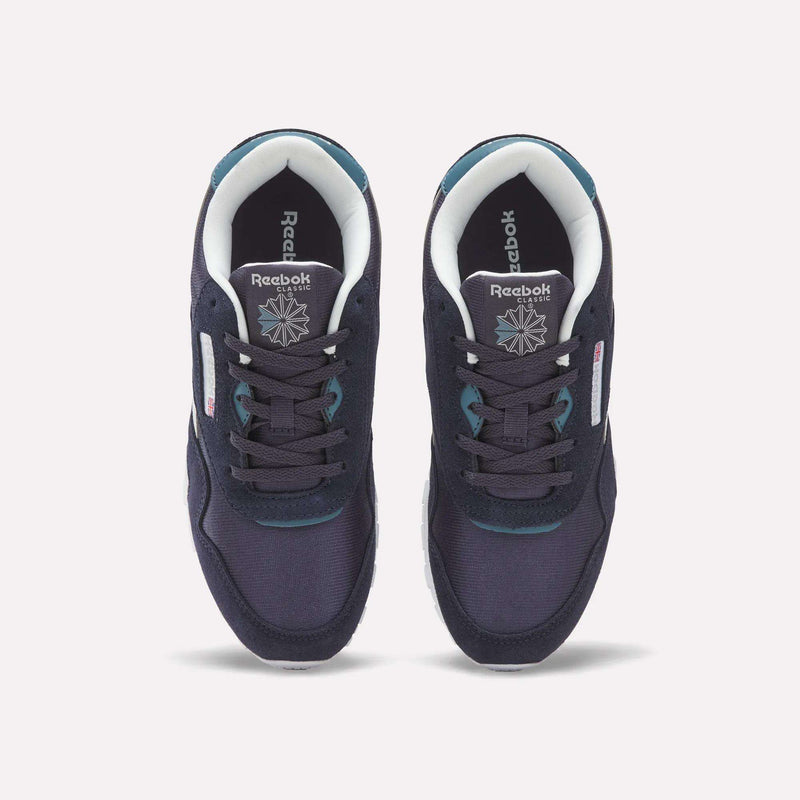 A pair of Reebok Classic Nylon Shoes - Big Kids in navy blue with white soles, seen from above. These boys’ shoes showcase teal accents, white lining, and feature the Reebok logo and star on the insoles.