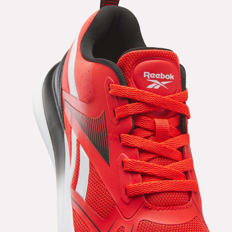 A close-up of the Reebok Rush Runner 6.0 Running Shoes for big kids, featuring a red design with white accents, black details, mesh and synthetic materials, red laces, an EVA midsole for comfort, and the Reebok logo on the tongue.