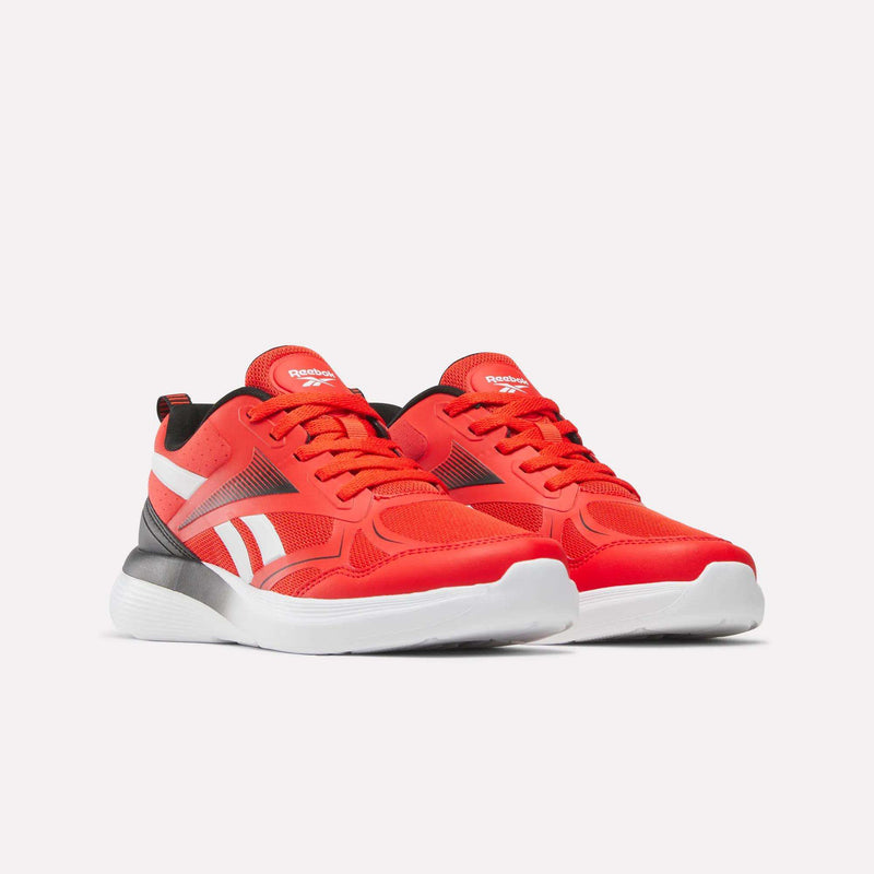 A pair of vibrant orange Rush Runner 6.0 Running Shoes by Reebok for big kids, featuring white soles and side stripes, black-and-white accents, a comfy EVA midsole, and the Reebok logo on the tongue, shown on a plain light background.