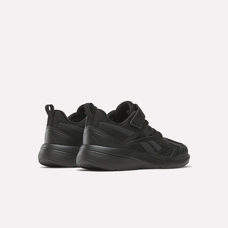 A pair of black Reebok Rush Runner 6.0 Elastic Lace Top Strap Running Shoes for little kids, shown from a rear-side angle on a light background. These low-top shoes have thick soles and subtle panel details, ideal for all-day play.