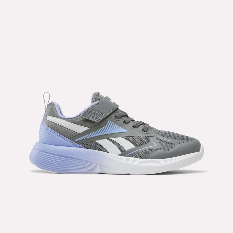 The Reebok Rush Runner 6.0 Elastic Lace Top Strap Running Shoes for little kids are gray athletic sneakers featuring light purple accents, a white midsole, and a distinctive white logo. Designed with a breathable mesh upper, convenient Velcro strap, and elastic lace-up closure, these shoes offer all-day comfort perfect for active youngsters. This stylish option from Reebok’s girls’ collection is displayed in a side view against a plain white background.
