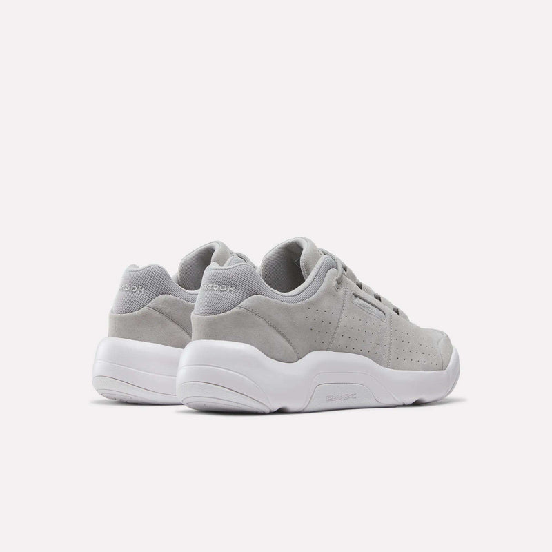 A pair of Reebok DMX Comfort+ Classic walking shoes in light gray with white soles, crafted from premium leather for a sleek finish, shown from the back and side against a plain white background.