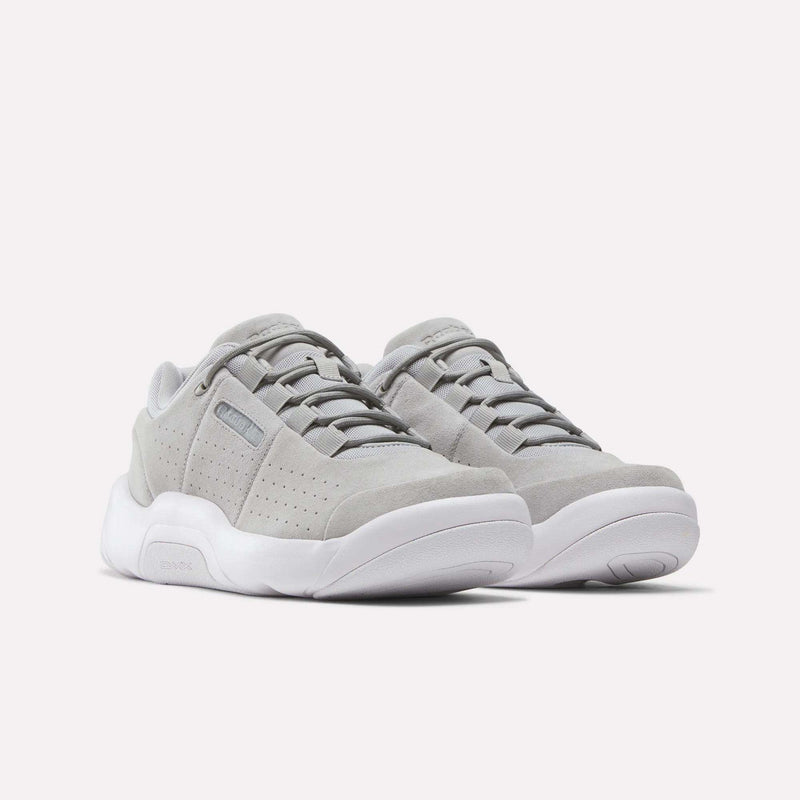 A pair of Reebok DMX Comfort+ Classic walking shoes in light gray suede with premium leather accents and white soles, shown from a front-side angle against a plain white background.